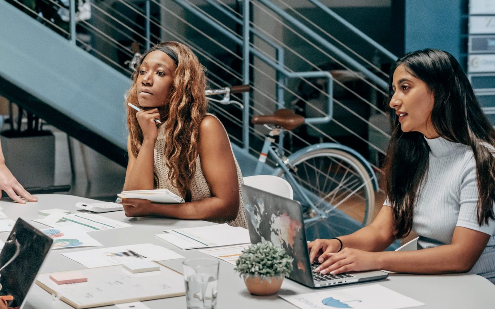 Two colleagues reviewing campaign plans and notes at a shared desk.