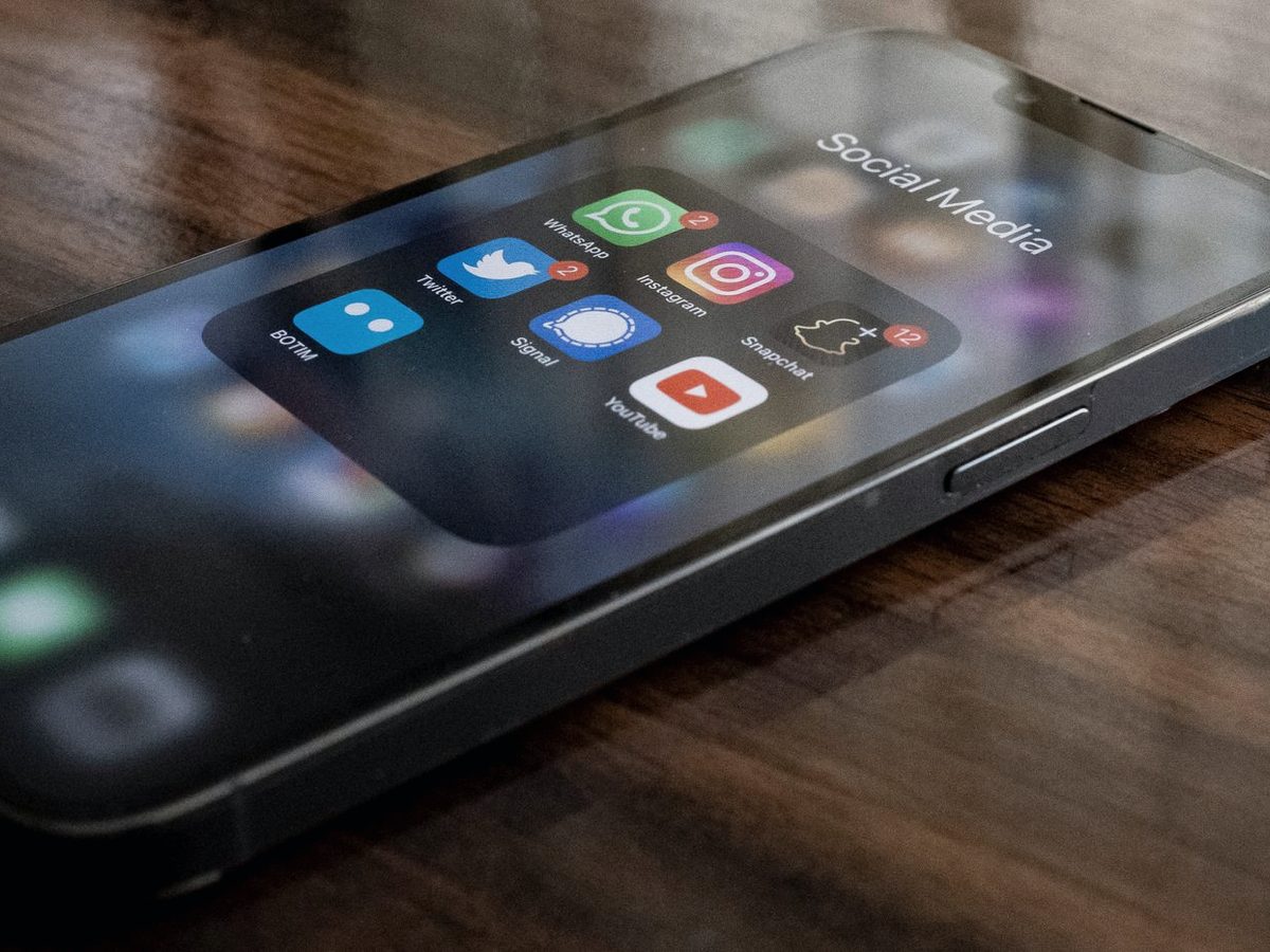 A smartphone on a desk showing a folder of social media applications.